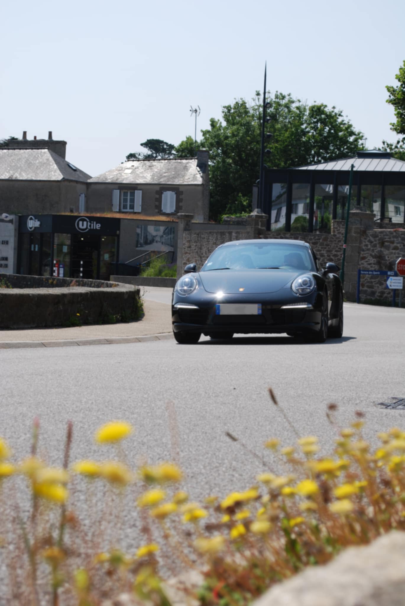 Voiture sportive moderne roulant sur une route côtière bretonne avec ciel nuageux